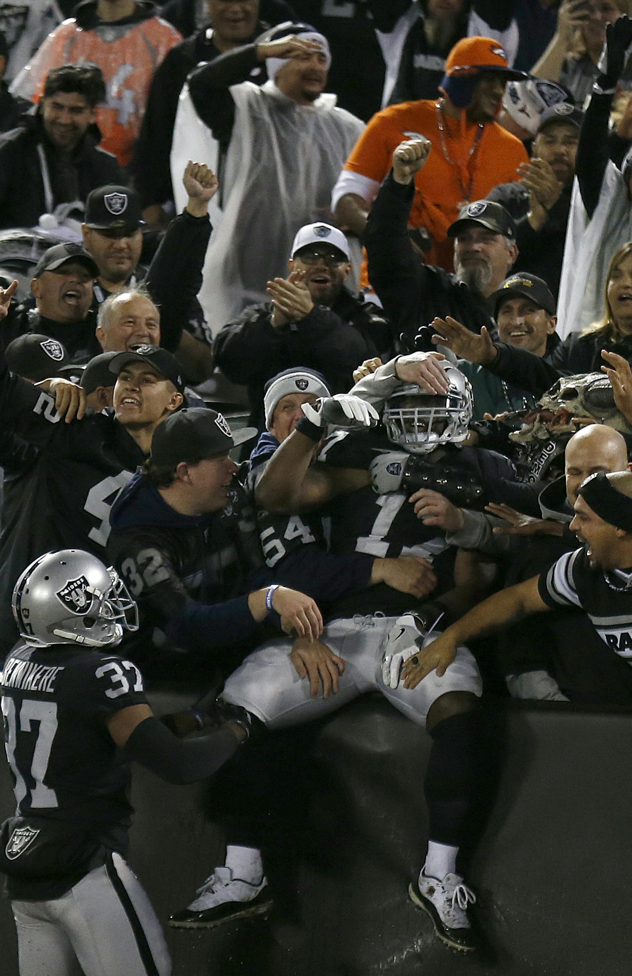 Oakland Raiders' Dwayne Harris, center, celebrates with fans after returning a punt for a touchdown against the Denver Broncos during the first half of an NFL football game in Oakland, Calif., Monday, Dec. 24, 2018. (AP Photo/D. Ross Cameron)
