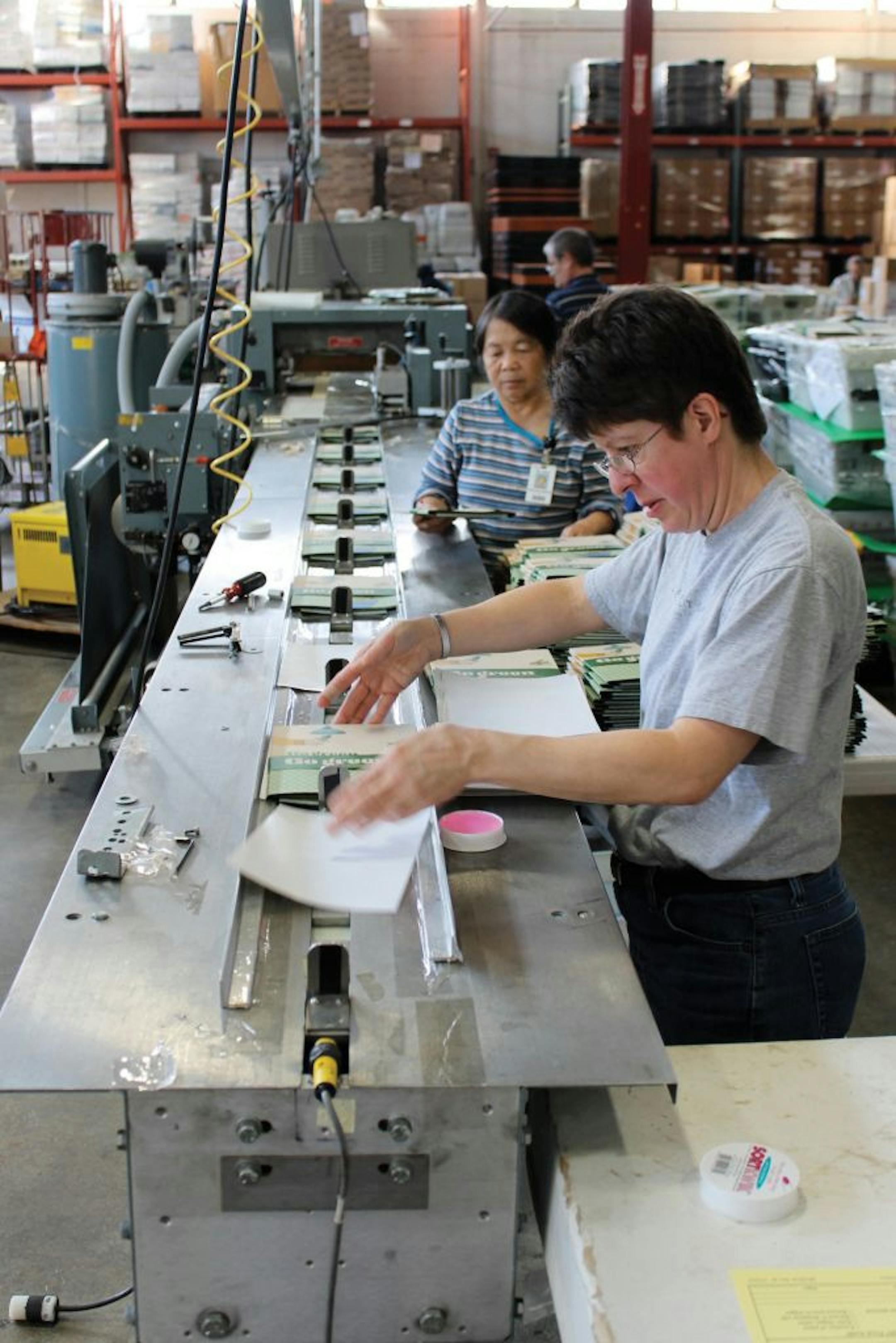 MDI employees Denise Pietsch, front, and Phoua Xiong working on the shrink-wrap line in St. Paul.