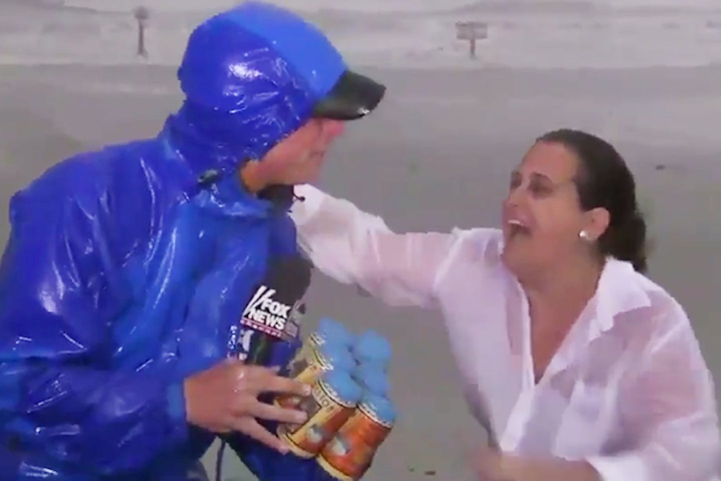 A Texas woman hands a six-pack of beer to a TV reporter during live coverage of Hurricane Harvey.