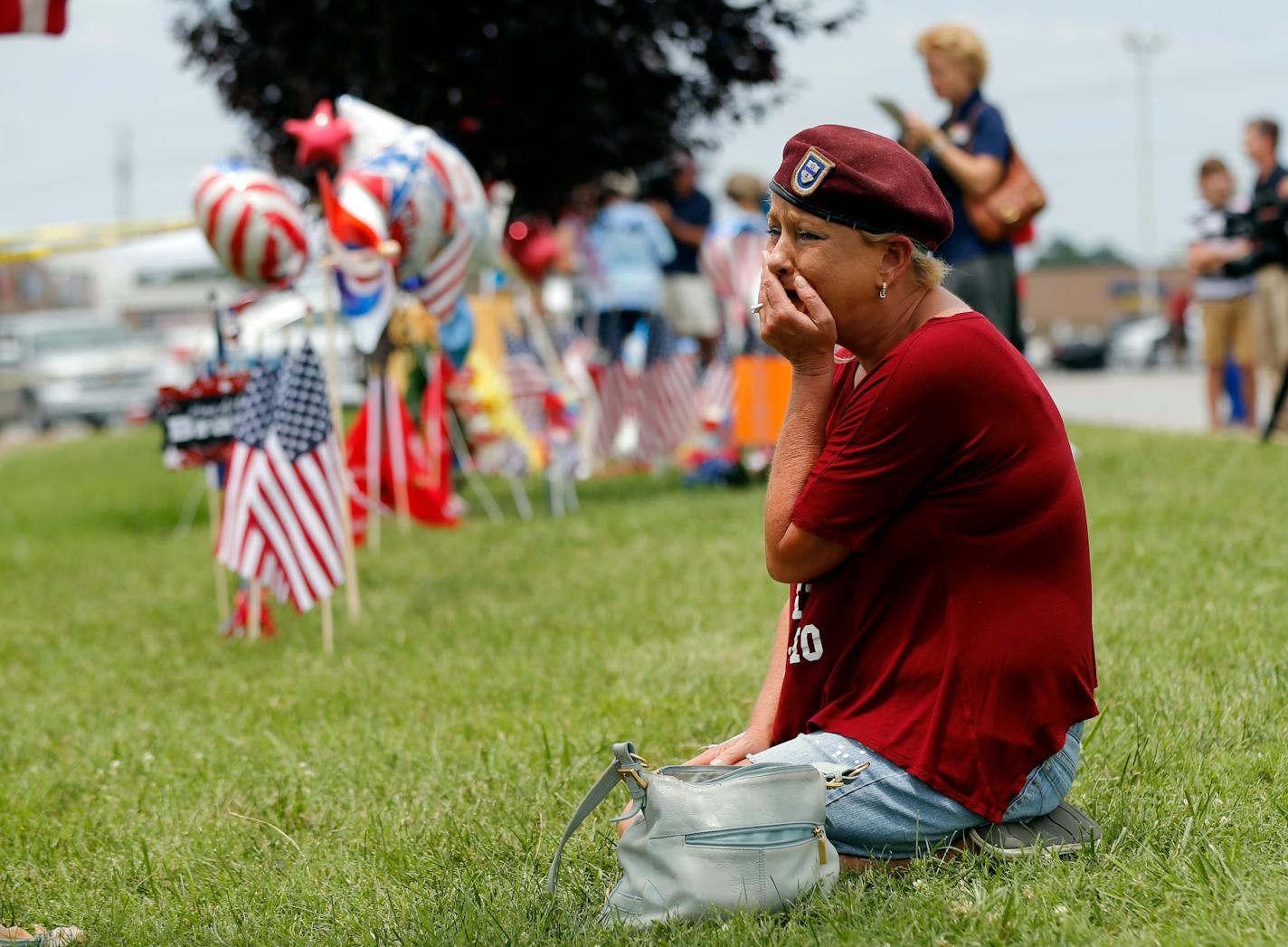 Laurie Norman becomes emotional as she looks at a makeshift memorial outside a military recruiting center Friday, July 17, 2015.