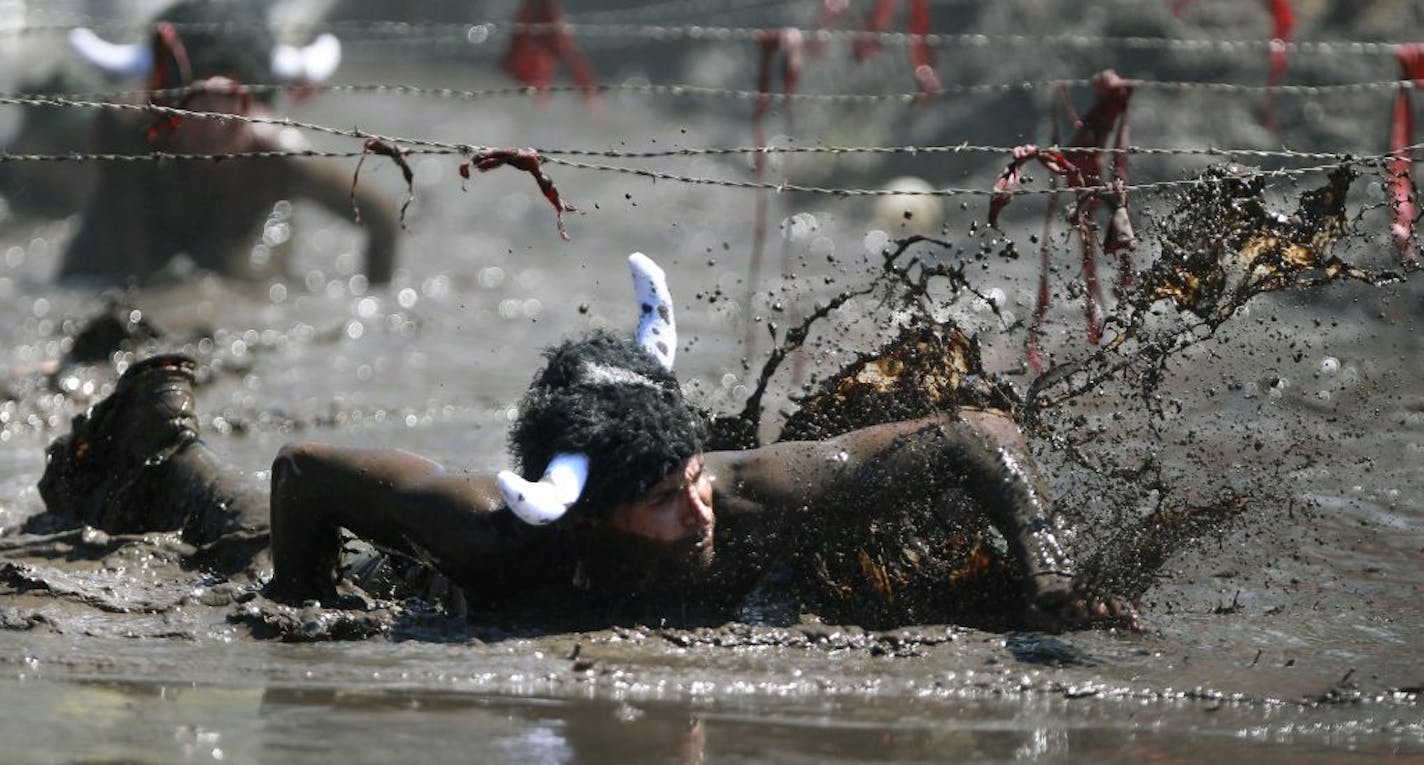 A Warrior Dash competitor made his way beneath wire and mud to finish the increasingly popular X-game style run on Sunday, July 24, 2011 at Afton State Park in Hastings, MN. The run is a three mile run that includes 11 different obstacles including jumping over cars and jumping over fire.