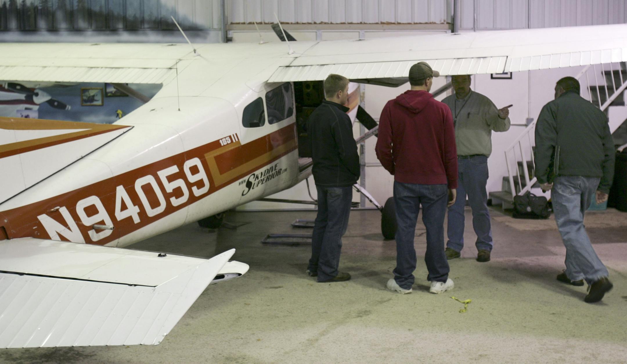 Two FAA investigators (right) meet with members of Skydive Superior on Sunday, Nov. 3, 2013 next to one of the planes involved in Saturday�s midair collision.