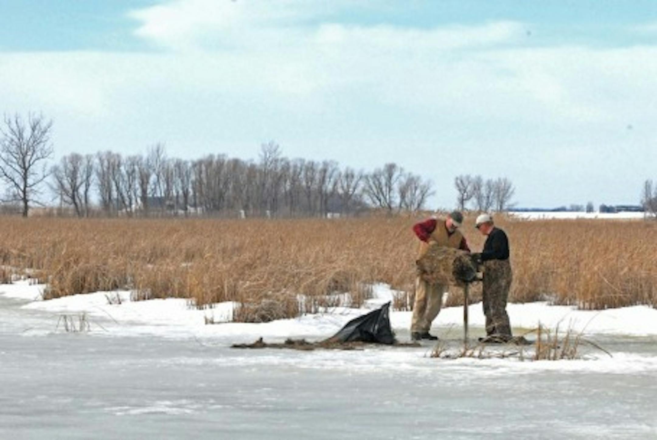 Two Delta Waterfowl employees place a hen house nesting cylinder in western Minnesota in anticipation of breeding ducks returning soon to the state.