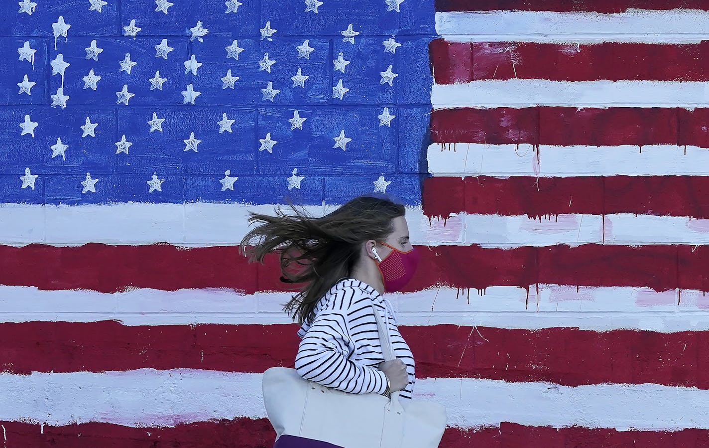 A woman walks past an American flag mural in San Francisco.