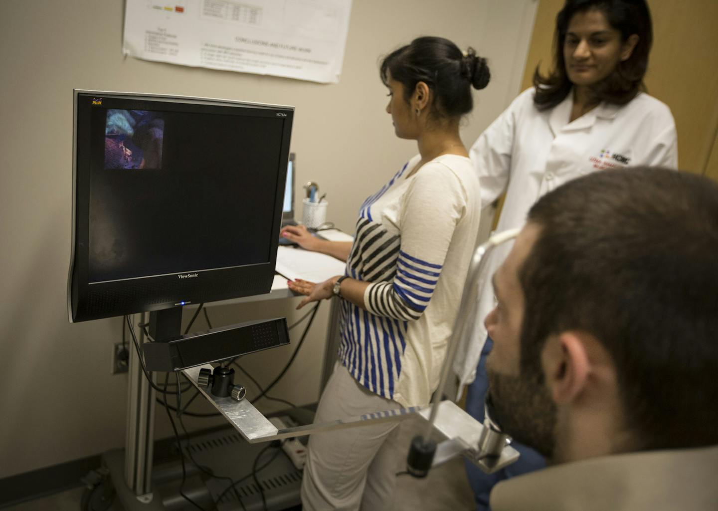 Dr. Uzma Samadani, middle, watched as research assistant Sam Daly, right foreground, sat through an eye test conducted by senior project coordinator Vikalpa Dammavalam, left, at HCMC on Wednesday, March 9, 2016, in Minneapolis, Minn. HCMC has been conducting eye tests on study participants including Daly, who works in the lab and is a former athlete, as part of research to identify better ways to detect concussion injuries and their long-term consequences. The test tracks both eye movements with