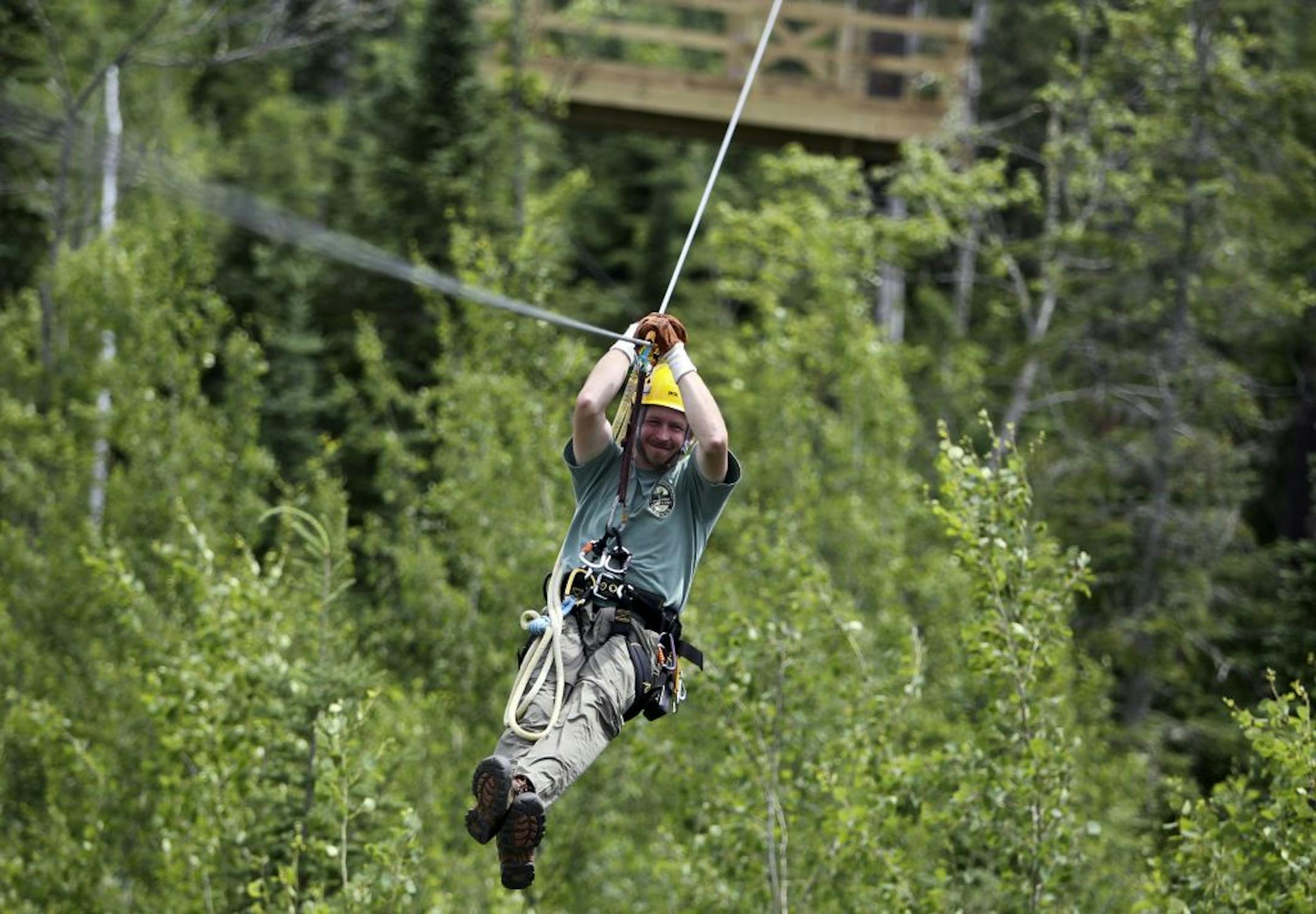 Jason Merrill, safety director for Up North: Minnesota Towering Pine Canopy Tours, heads down a zip line.
