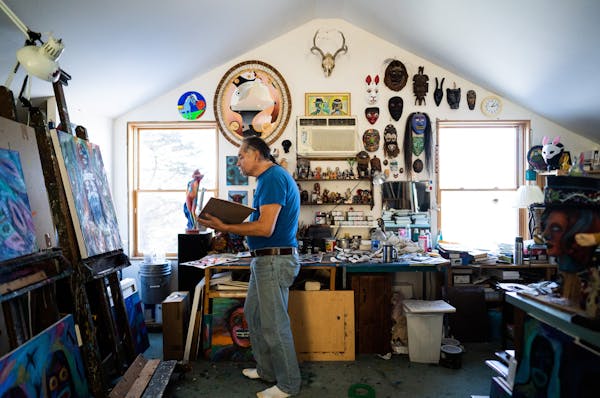 Denomie work surrounded by his own paintings and a vast collection of masks. ] MARK VANCLEAVE ¥ Minnesota artist Jim Denomie works in his Shafer, Min