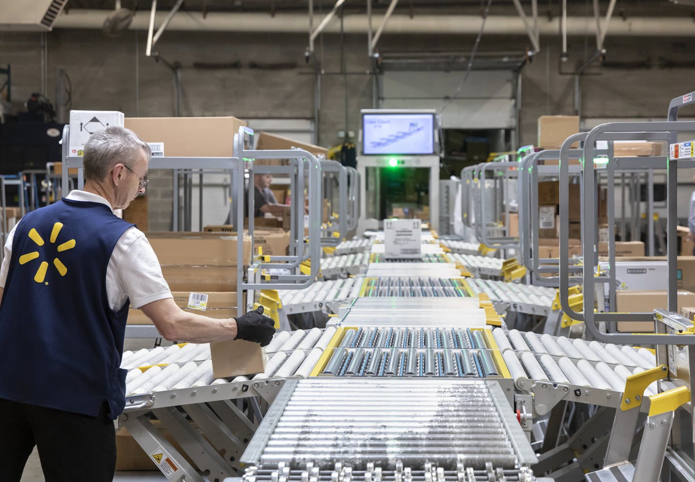 Doug Jones, a stocker and unloader at the Bonney Lake Walmart, takes an item off the end of the FAST unloader, a new device that changes the way they unload trucks to the store. FAST stands for flexible automated sorting technology, and it&#xe2;&#x20ac;&#x2122;s a large conveyor belt system that scans items and puts them in organized areas for shelving. The upgrades are part of a $36 million investment in new technologies and upgrades to Walmarts in Washington state (Bettina Hansen / The Seattle