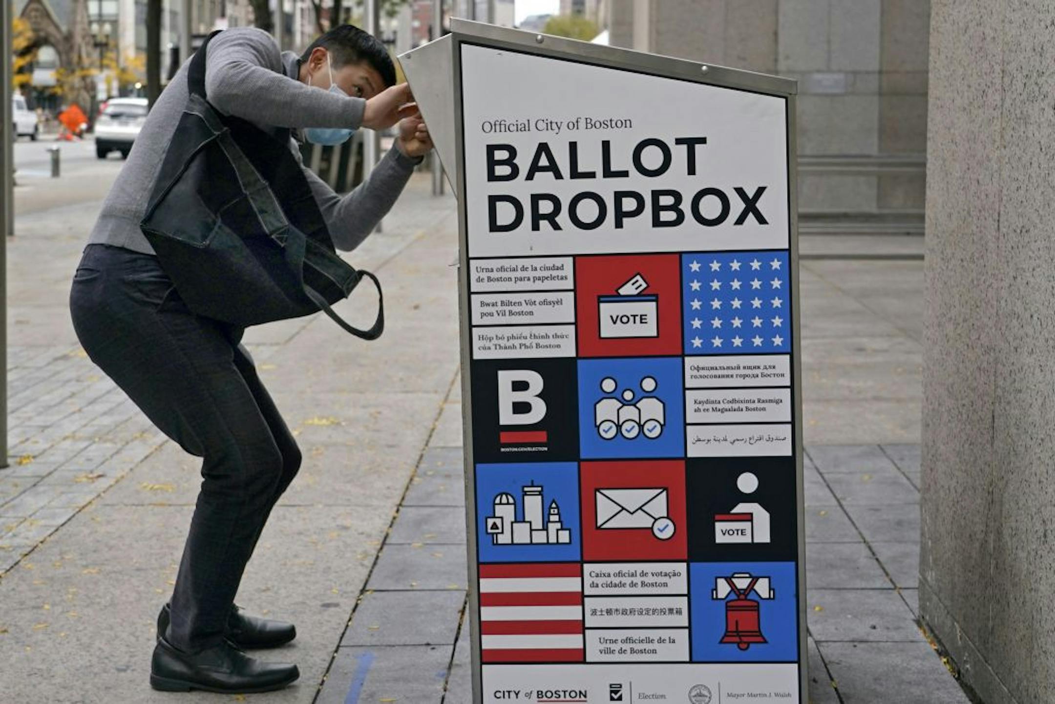 A voter makes sure his ballot falls into the ballot drop box outside the Boston Public Library, Monday, Oct. 26, 2020, in Boston. Massachusetts election officials say a fire was set in the ballot drop box Sunday, holding more than 120 ballots in what appears to have been a "deliberate attack." The FBI says it is investigating.
