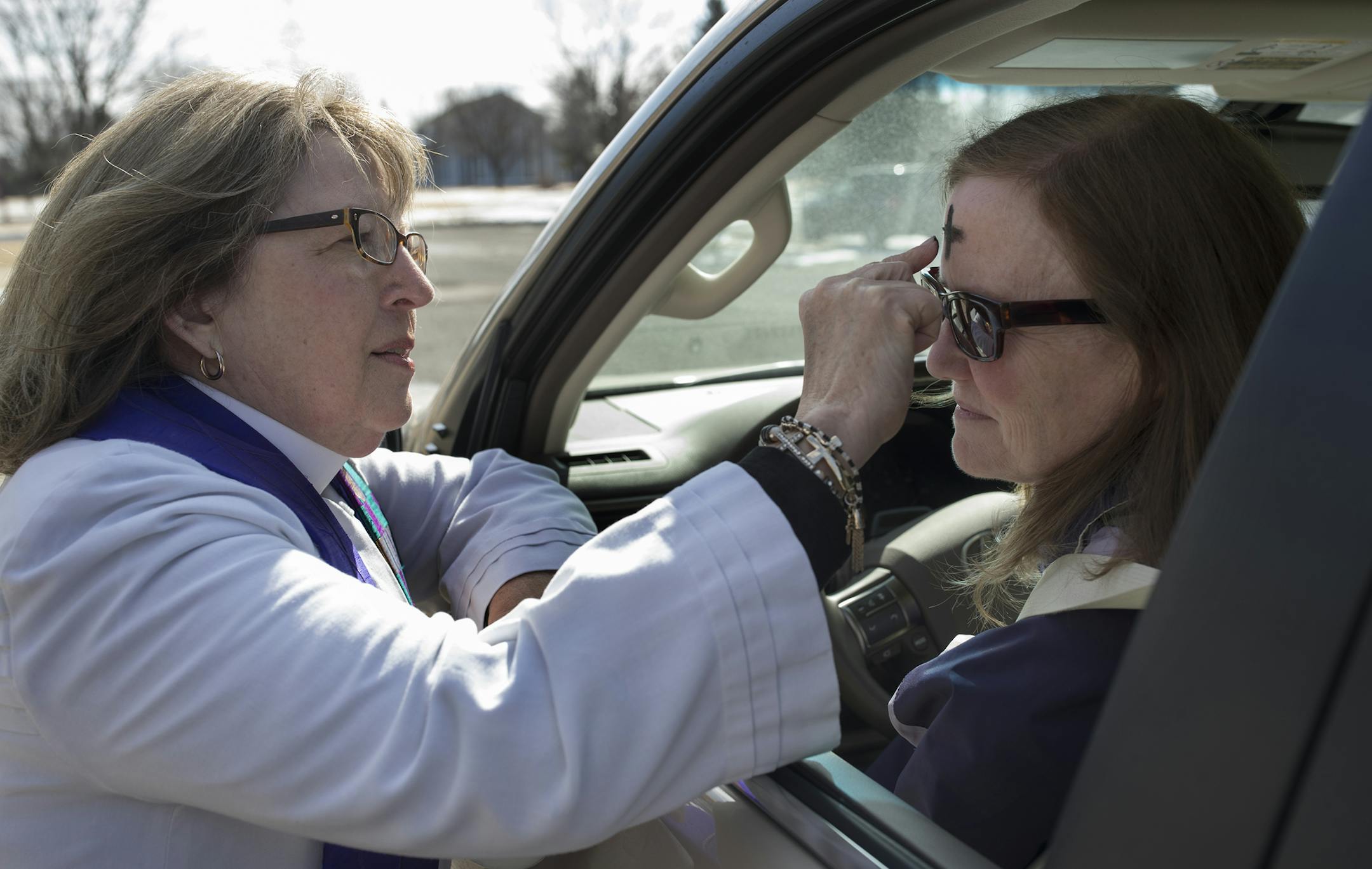Pastor Christine Chiles put a cross on the forehead of Noreen Faulkner of Plymouth during a drive through service of Ash Wednesday March 1, 2017 in at Maple Grove Lutheran Church in Maple Grove, MN.] JERRY HOLT ï jerry.holt@startribune.com