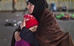 Syrian refugee girl Sondos Almasri, 9, who suffers from cold, is comforted by her mother after spending the night at a collection point in the truck p