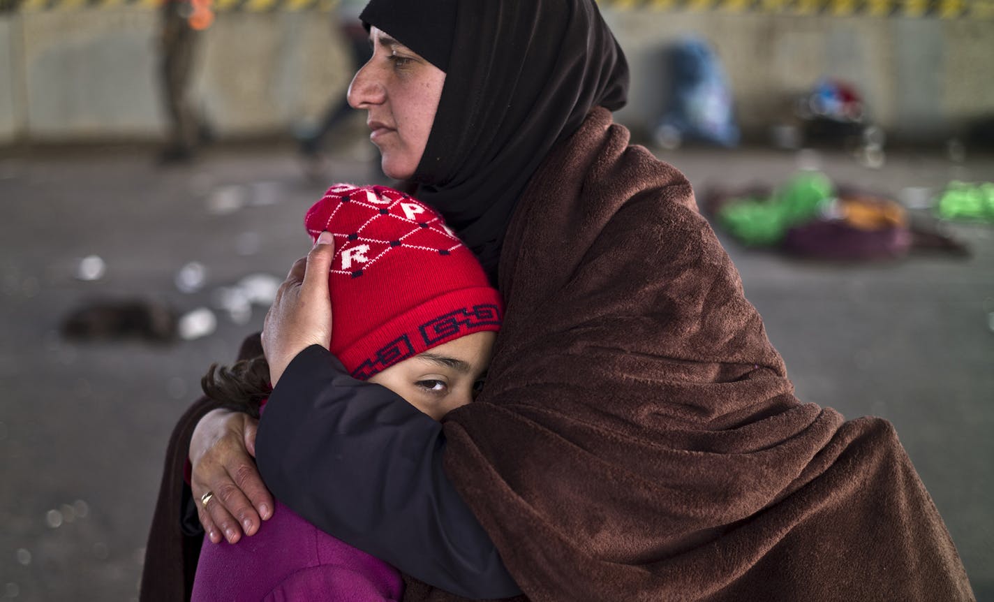 Syrian refugee girl Sondos Almasri, 9, who suffers from cold, is comforted by her mother after spending the night at a collection point in the truck parking lot of the former border station on the Austrian side of the Hungarian-Austrian border near Nickelsdorf, Austria, Wednesday, Sept. 23, 2015. European Union ministers agreed Tuesday to relocate 120,000 migrants in a move intended to ease the strain on nations Greece and Italy which are on the frontline of the continent&#xed;s overwhelming mig