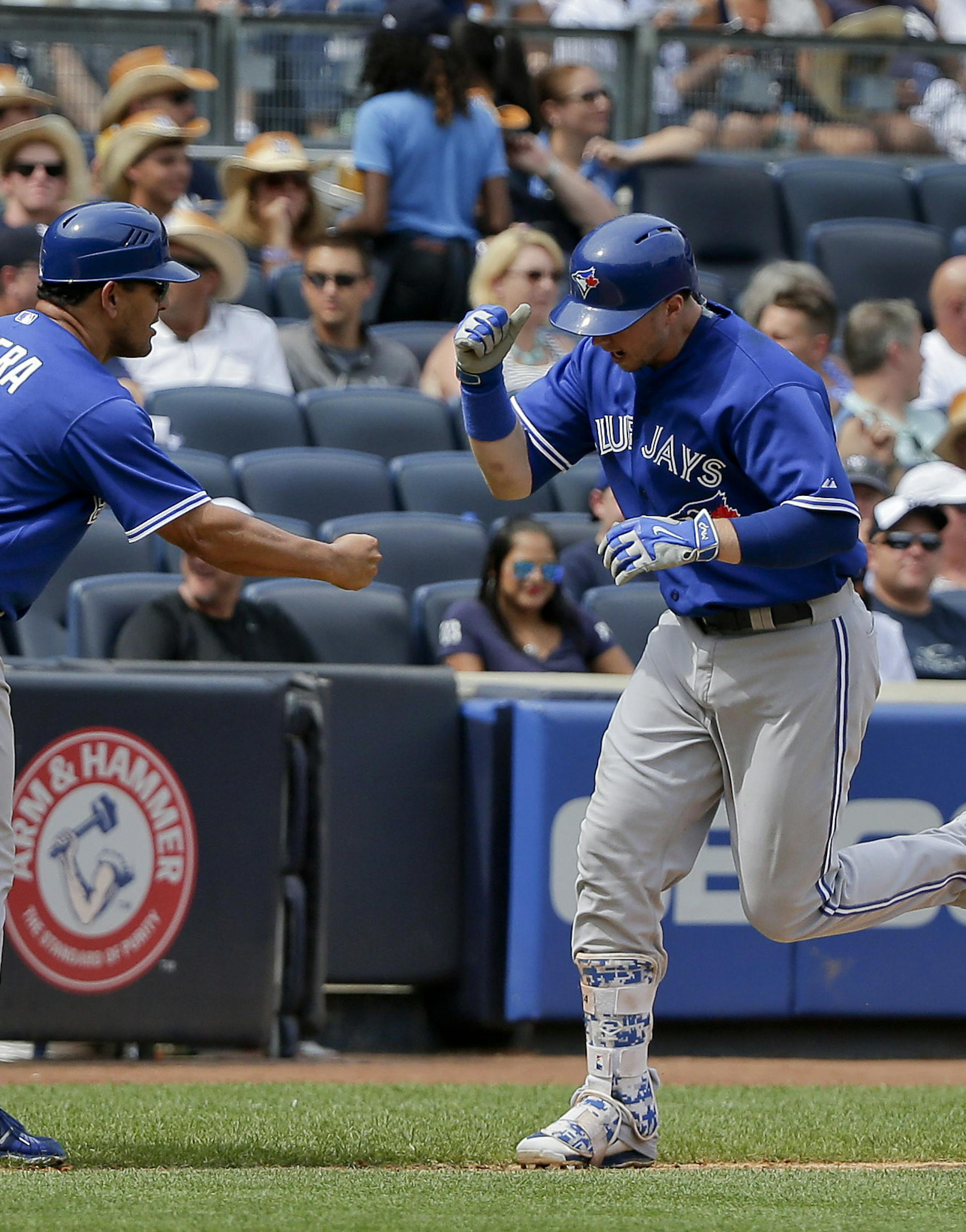 Toronto Blue Jays' Justin Smoak is congratulated by third base coach Luis Rivera (4) after hitting a grand slam home run against the New York Yankees during the sixth inning of a baseball game, Saturday, Aug. 8, 2015, in New York. (AP Photo/Julie Jacobson)