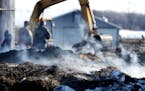 Fire smolders as workers clean up debris from the fire-gutted barn of Ray and Cindy Deutsch where a fire last week killed 63 of their dairy cattle and