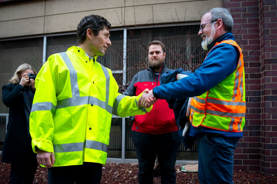 Mayor of Minneapolis Jacob Frey shook hands with Brette Hjelle, the Interim Director of Public Works, after filling a pothole in downtown on Thursday. The team of public workers behind him has filled 9,359 potholes thus far.