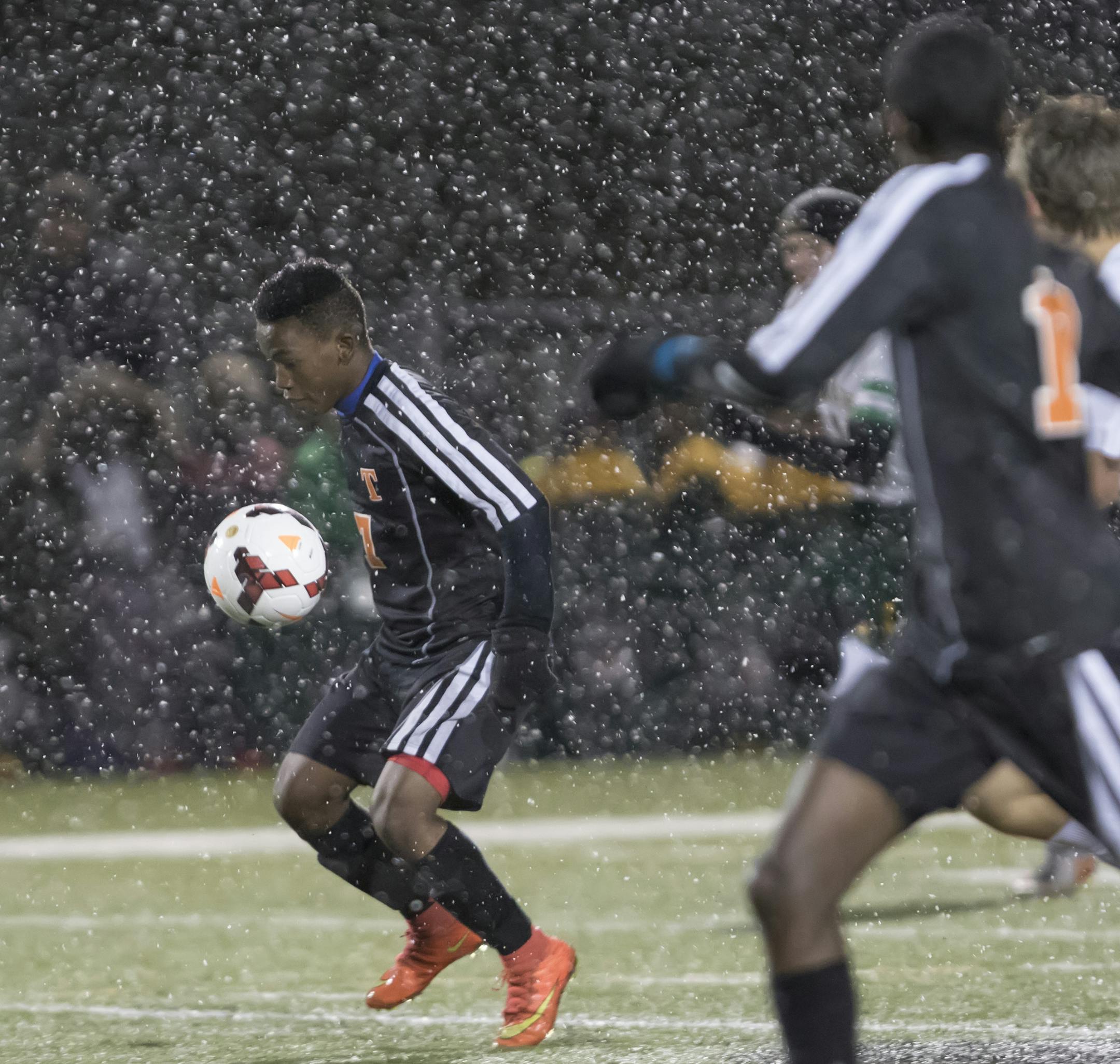 St. Cloud Tech forward Khalid Gelani (7) advances the ball in the snow as the Park Center Pirates faced the St. Cloud Tech Tigers in the 2015 MSHSL Boys' soccer playoffs. ] MATT BLEWETT ï matt@mattebphoto.com - October 28, 2015, Farmington, MN, Park Center Pirates, St. Cloud Tech Tigers, Prep Soccer, Park Center Pirates vs St. Cloud Tech Tigers