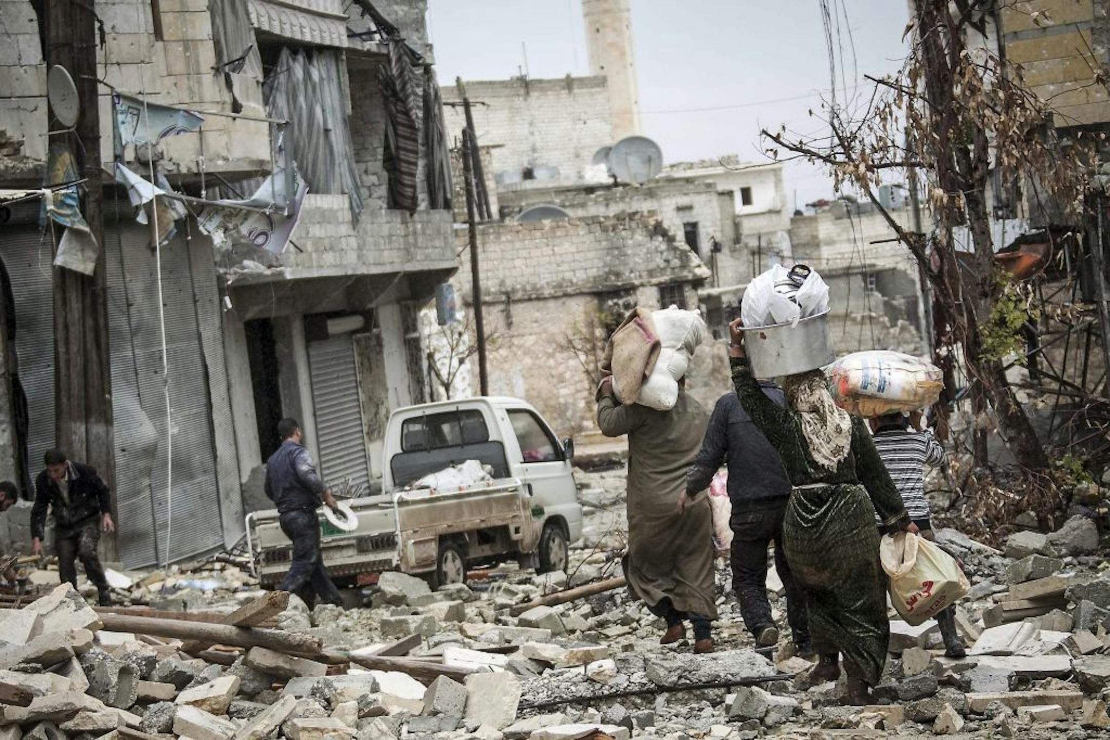 In this Tuesday, Dec. 11, 2012 photo, Syrian residents carry their belongings after their homes were damaged due to fighting between Free Syrian Army fighters and government forces in Aleppo, Syria.