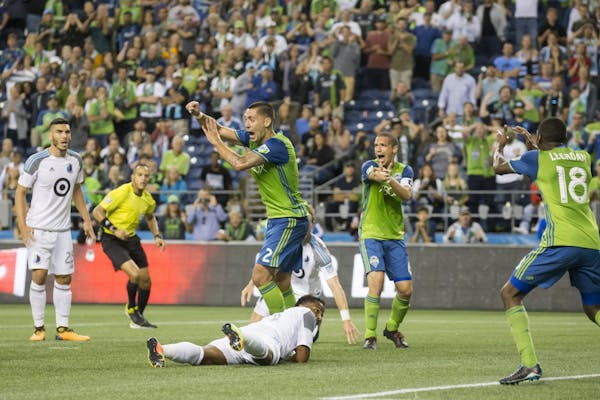 Seattle Sounders forward Clint Dempsey signals for a handball in the box by Minnesota United defender Jermaine Taylor,on ground, during stoppage time 