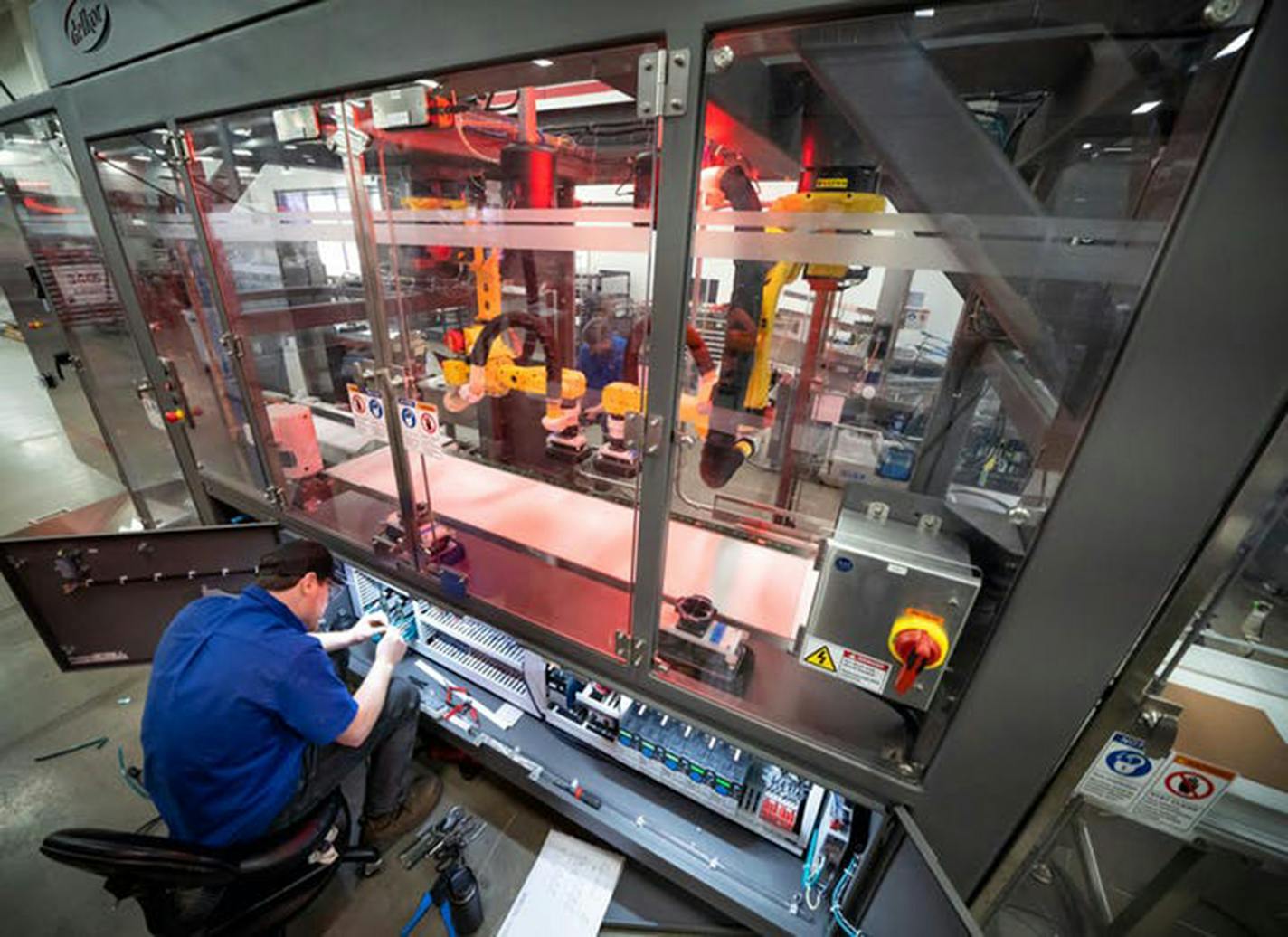 Dylon Eisele worked on the control panel of a Delkor case loader last spring. Delkor's robotic packaging machines are in hgih demand as food companies try to meet urgent orders from grocery stores.