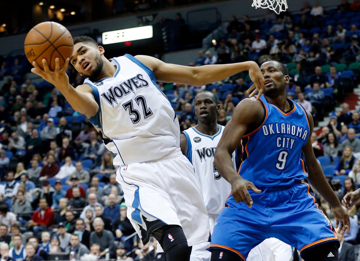Karl-Anthony Towns, left, tries to control the ball on a rebound as Oklahoma City Thunder's Serge Ibaka looks on.