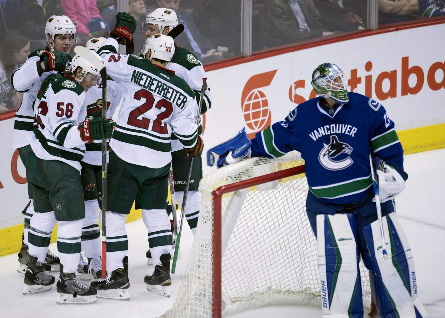 Teammates mobbed Wild right winger Justin Fontaine, rear, who scored against Vancouver goalie Jacob Markstrom for a 3-1 lead in the second period.