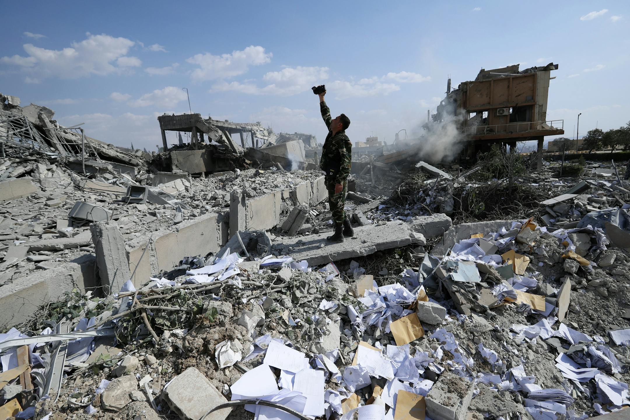 A Syrian soldier films the damage of the Syrian Scientific Research Center which was attacked by U.S., British and French military strikes to punish President Bashar Assad for suspected chemical attack against civilians, in Barzeh, near Damascus, Syria, Saturday, April 14, 2018. The Pentagon says none of the missiles filed by the U.S. and its allies was deflected by Syrian air defenses, rebutting claims by the Russian and Syrian governments. Lt. Gen. Kenneth McKenzie, the director of the Joint S
