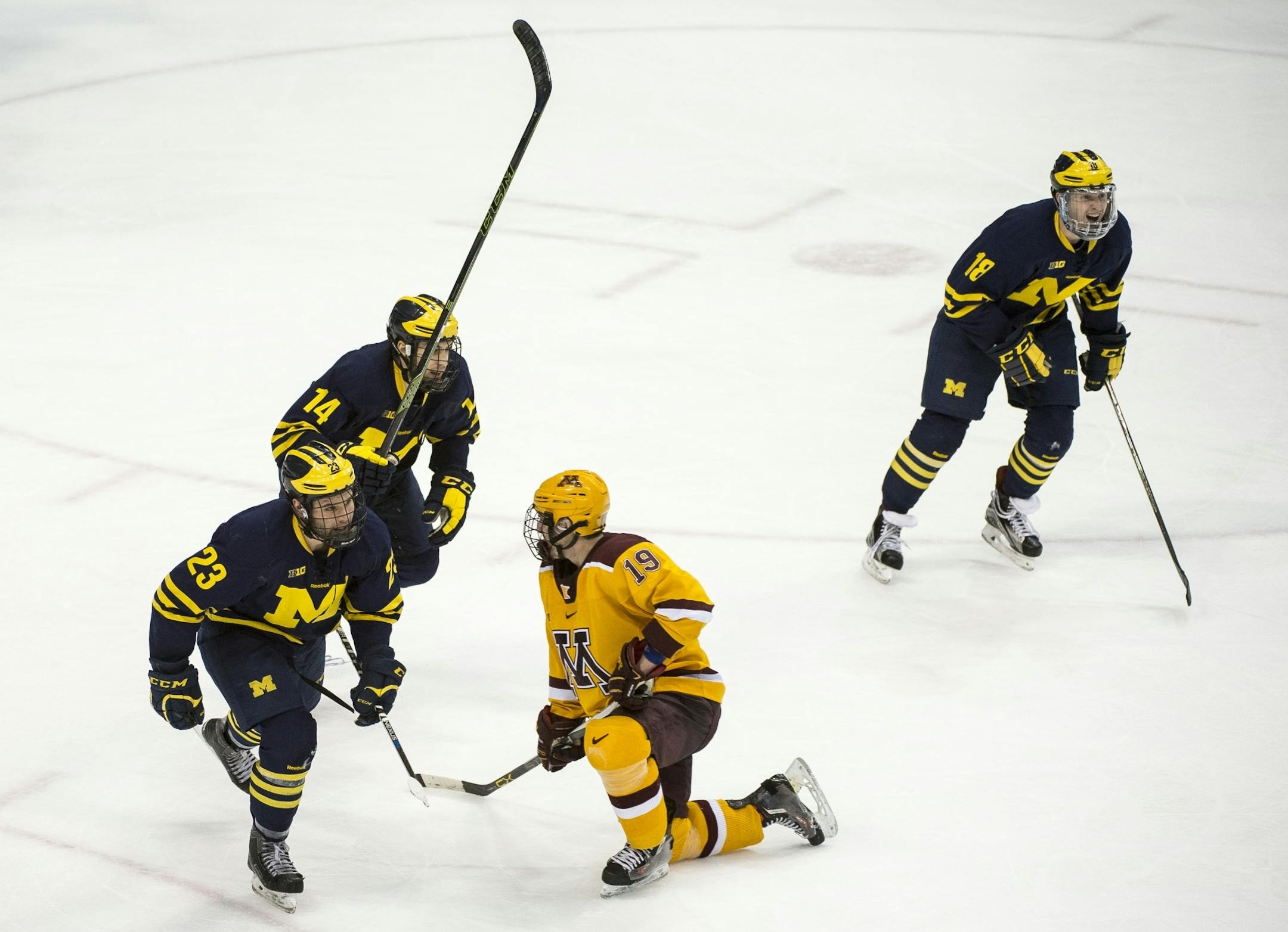 Minnesota Golden Gophers center Vinni Lettieri (19) was dejected as Michigan Wolverines forward Alex Kile (23), forward Tyler Motte (14), and forward Kyle Connor (18) celebrated a goal by Connor in the third period, giving the Wolverines a 4-3 lead over the Minnesota Golden Gophers.