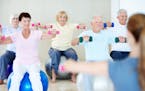 A group of elderly people lifting weights together in a fitness class