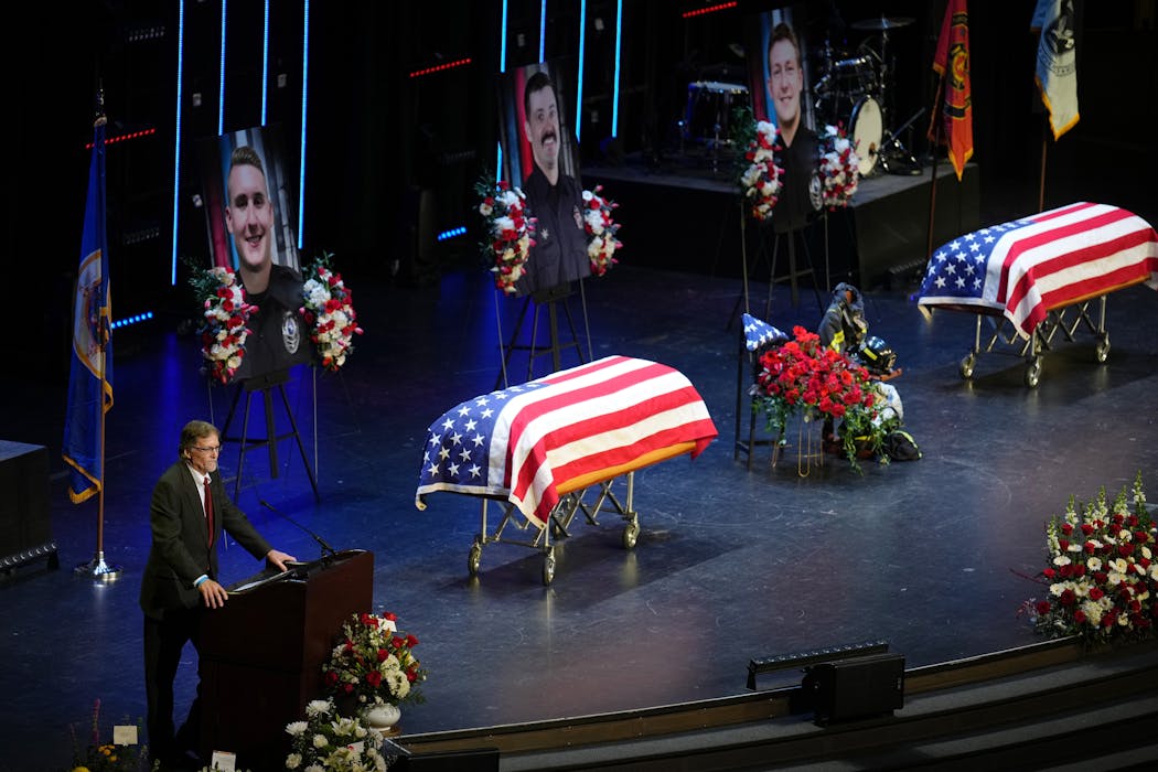 Brad Finseth, left, speaks during the memorial service for his son, firefighter-paramedic Adam Finseth, 40, pictured at top center, and Burnsville police officers Paul Elmstrand, 27, pictured at top left, and Matthew Ruge, 27, pictured at top right, at Grace Church in Eden Prairie on Feb. 28.

