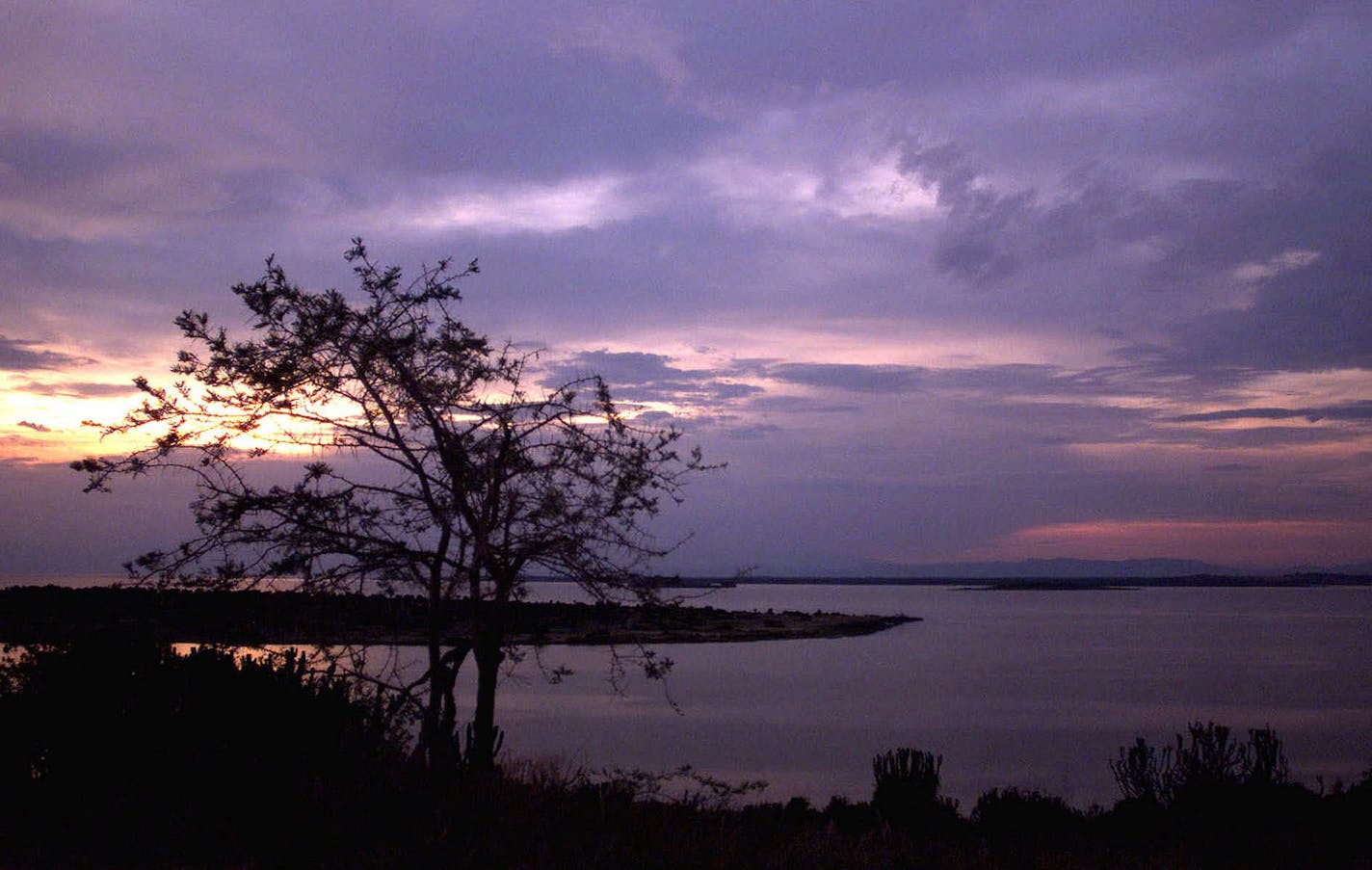 The sun sets over Lake George near Uganda's Queen Elizabeth National Park in western Uganda, near Myeya, Wednesday, April 5, 2000. The pristine landscapes and wild game parks of Uganda's west are a major source of tourist dollars for the nation. Despite several headline-commanding negative events in the past several years and decades, Uganda is in fact one of the most stable, peaceful, and economically-healthy nations in Africa. (AP Photo/Brennan Linsley) ORG XMIT: NY121,NY121