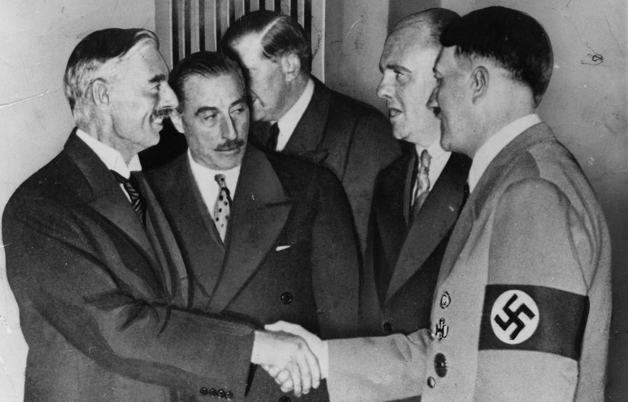 British Premier Sir Neville Chamberlain shakes hands with German leader Adolf Hitler, sealing a peace treaty, in Munich, Germany, September 30, 1938. Chamberlain was successful in his peace saving effort in conjunction with the French, German and Italian heads of state. The pact was one of several diplomatic successes that strengthened Hitler's hold on Germany, expanded his European power and set the stage for conquest in Europe. Next to Hitler stands interpreter Paul Schmidt, and British ambass