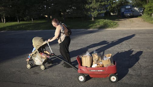 Tara Nordgren walked home with her son Allan in a stroller and a wagon she had attached by a belt to the handle of the stroller to bring home the groceries she had got at the Anoka County Brotherhood Council food shelf in Anoka, Minn., on Thursday, June 18, 2015. Nordgren works at Burger King but as a single mom needs help with groceries since her food stamps were cut back. She doesn't own a car. ] RENEE JONES SCHNEIDER &#x2022; reneejones@startribune.com