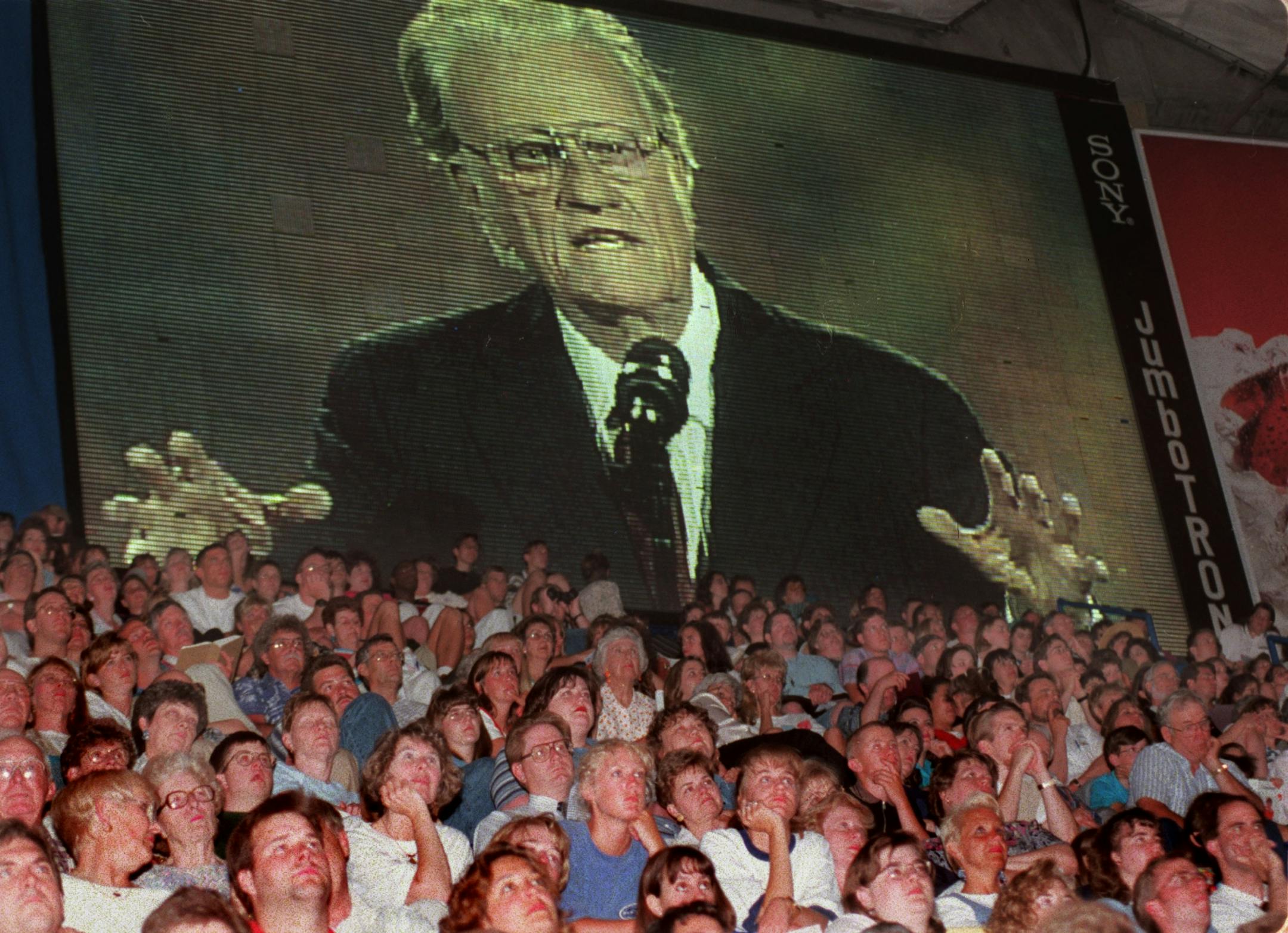Billy Graham begins his sermon as seen from oversized video screen in left fiels of the Metrodome