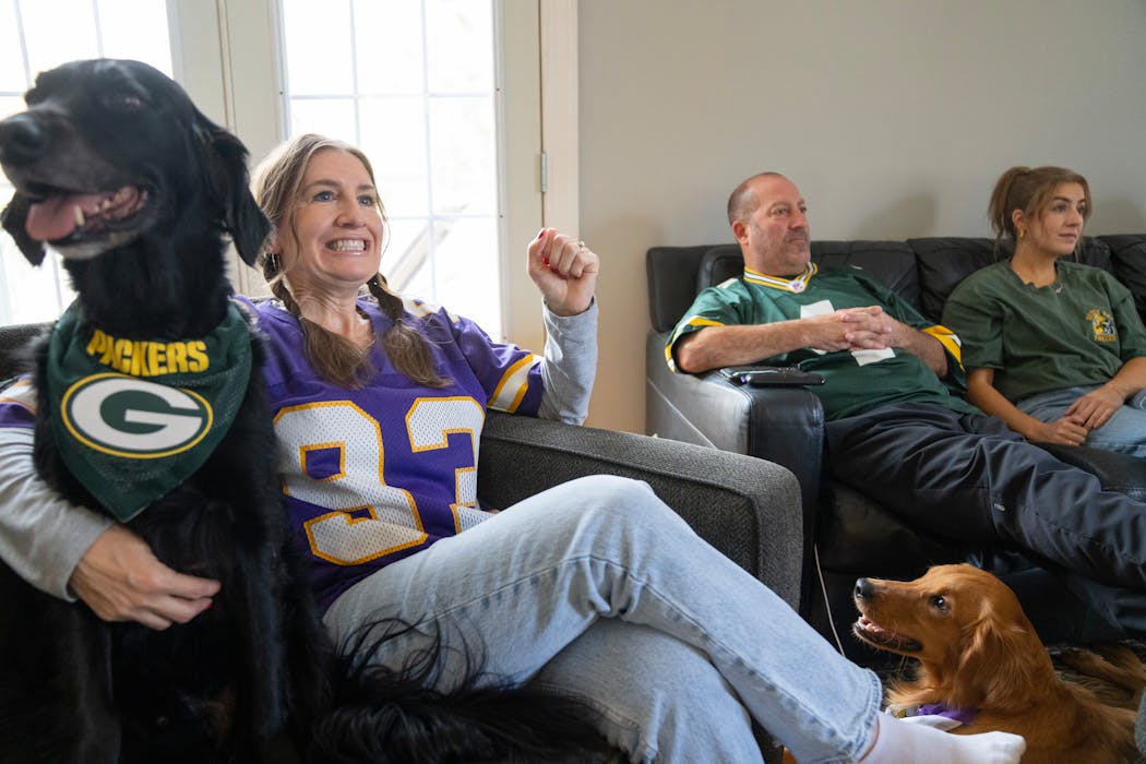 Jenn Russo sat with one of the family dogs, Cooper, as she celebrated a big play for the Vikings, while her husband, Paul, and their daughter, Olivia, watched with Tucker, the other family dog, during the Packers v. Vikings game Sunday.