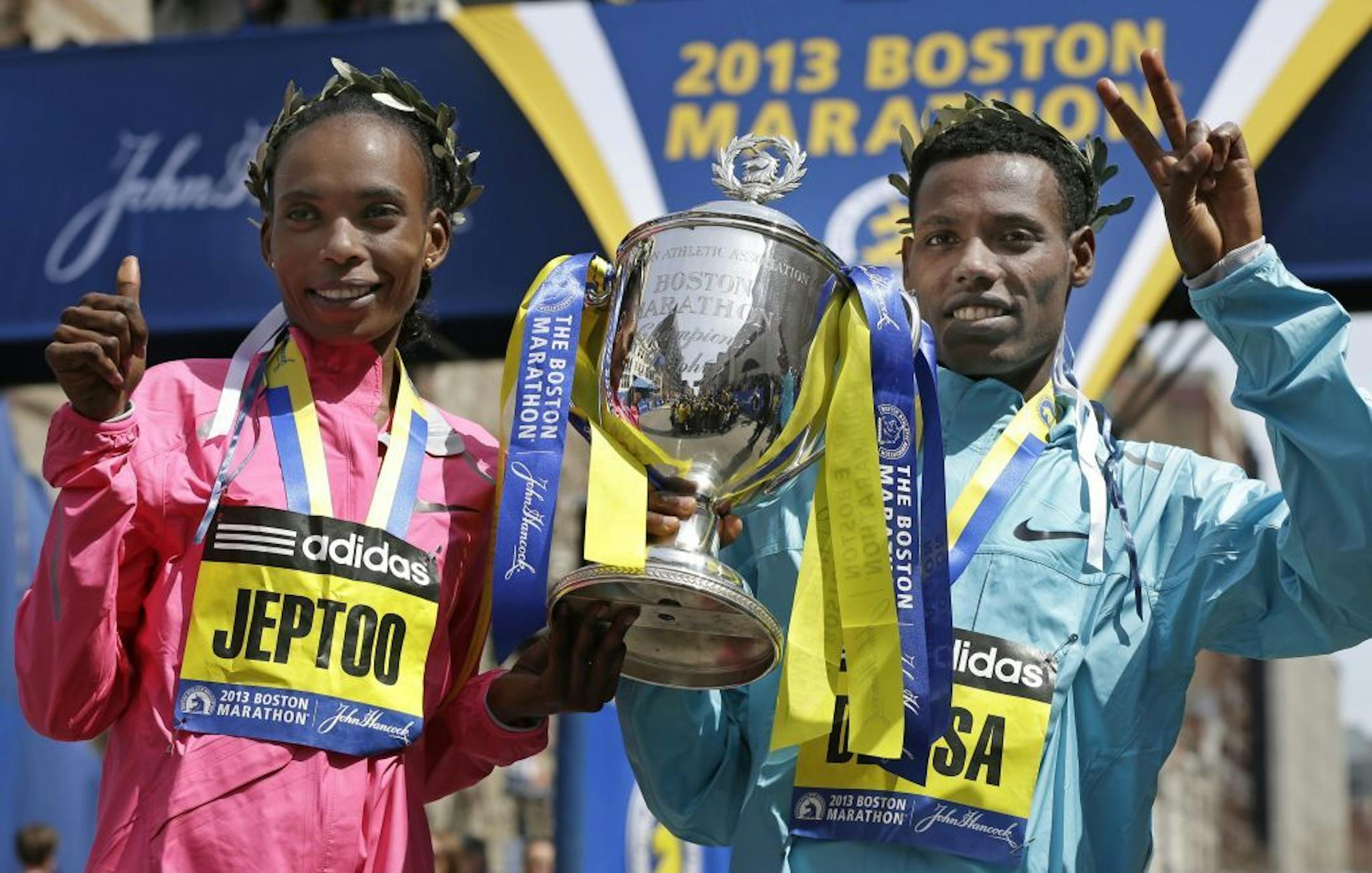 Rita Jeptoo of Kenya and Lelisa Desisa of Ethiopia pose with a trophy at the finish line after winning the women's and men's divisions of the 2013 Boston Marathon in Boston Monday, April 15, 2013.