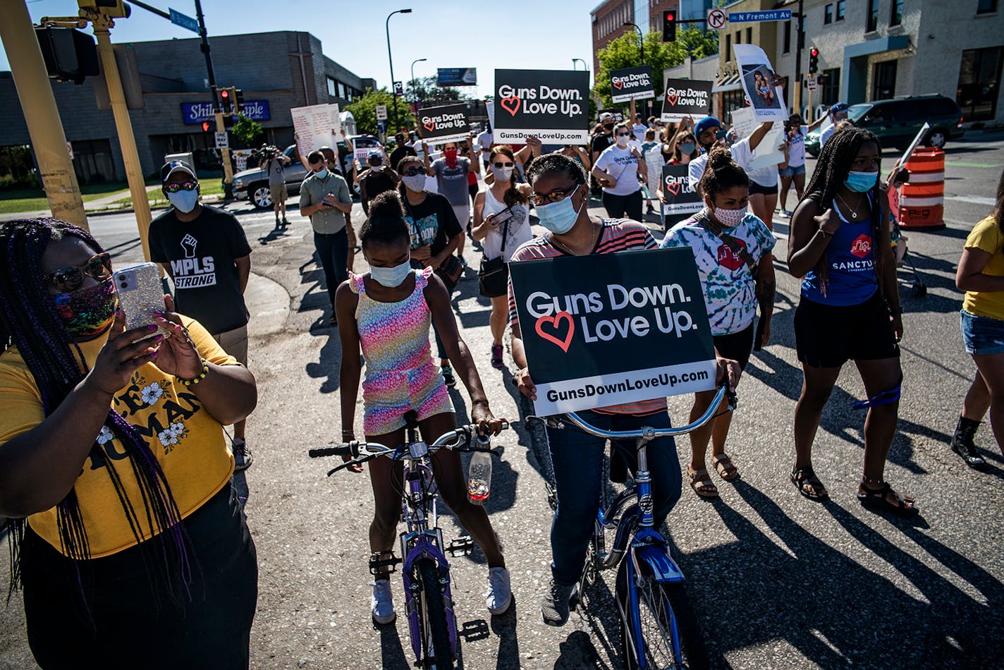 Nekima Levy Armstrong, left, who was livestreaming to Facebook next to Savitta Ford and her daughter, Harmony,11, joined the rally on Broadway because just two blocks from their home someone on a bicycle was shot and injured.