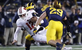 Wisconsin quarterback Alex Hornibrook (12) is brought down by Michigan linebacker Devin Bush (10) in the first half of an NCAA college football game i