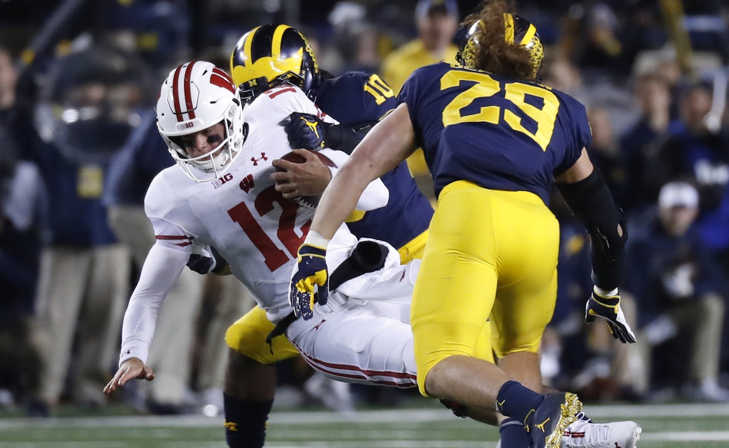 Wisconsin quarterback Alex Hornibrook (12) is brought down by Michigan linebacker Devin Bush (10) in the first half of an NCAA college football game in Ann Arbor, Mich., Saturday, Oct. 13, 2018. (AP Photo/Paul Sancya)