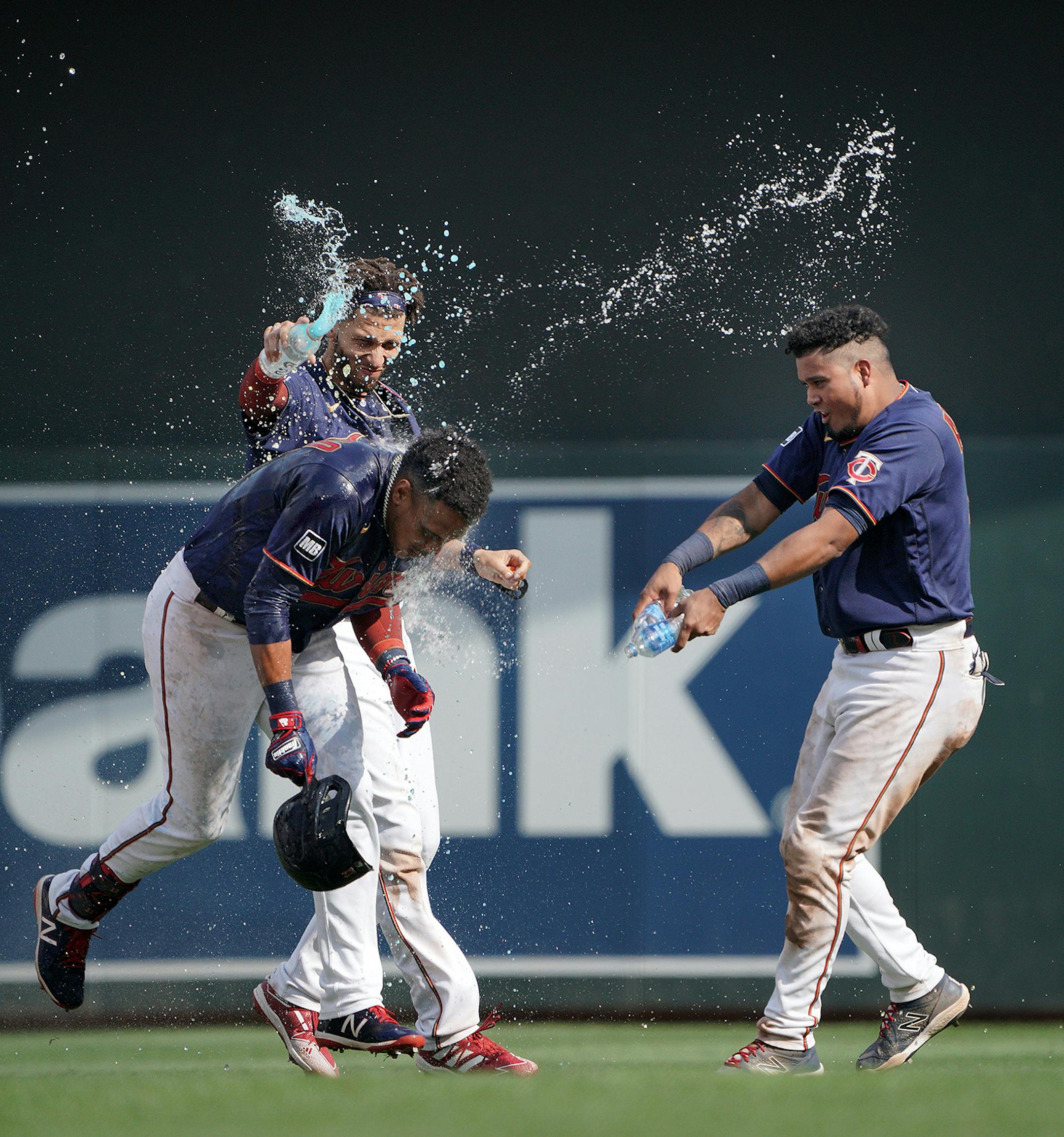 Minnesota Twins' Jorge Polanco, (left front),gets a water shower from his teammates after his bases-loaded, walk off single drove in the winning run in the 11th inning as the Twins beat the Cleveland Indians 8-7.