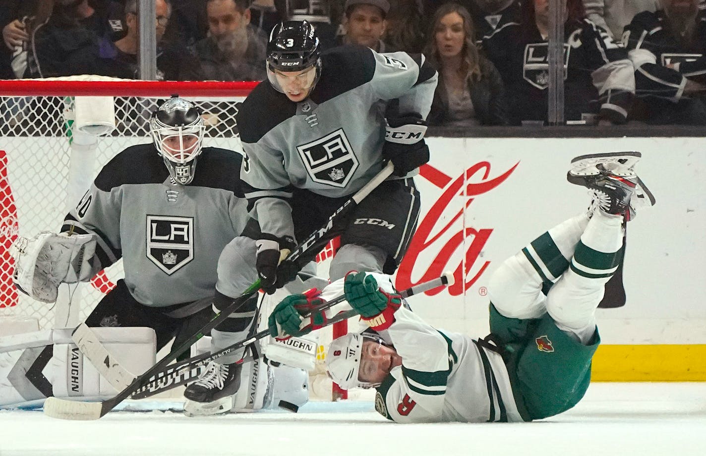 Los Angeles Kings defenseman Matt Roy, center, helps stop a shot as Wild center Ryan Donato, right, falls to the ice.