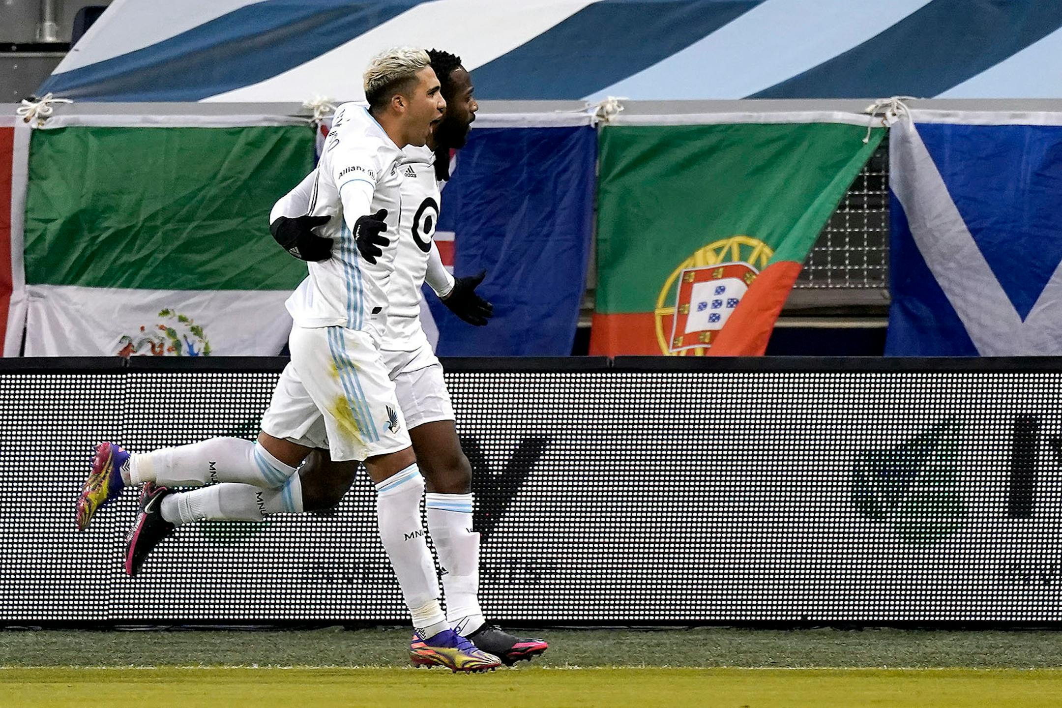 Minnesota United midfielder Kevin Molino, back, celebrates with midfielder Emanuel Reynoso after scoring a goal during the first half of the team's MLS soccer match against Sporting Kansas City on Thursday, Dec. 3, 2020, Kansas City, Kan. (AP Photo/Charlie Riedel)