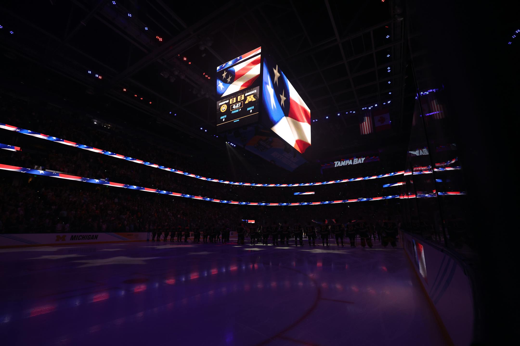 Minnesota and Quinnipiac men's hockey players stand for the National Anthem before the finals of the NCAA Frozen Four.