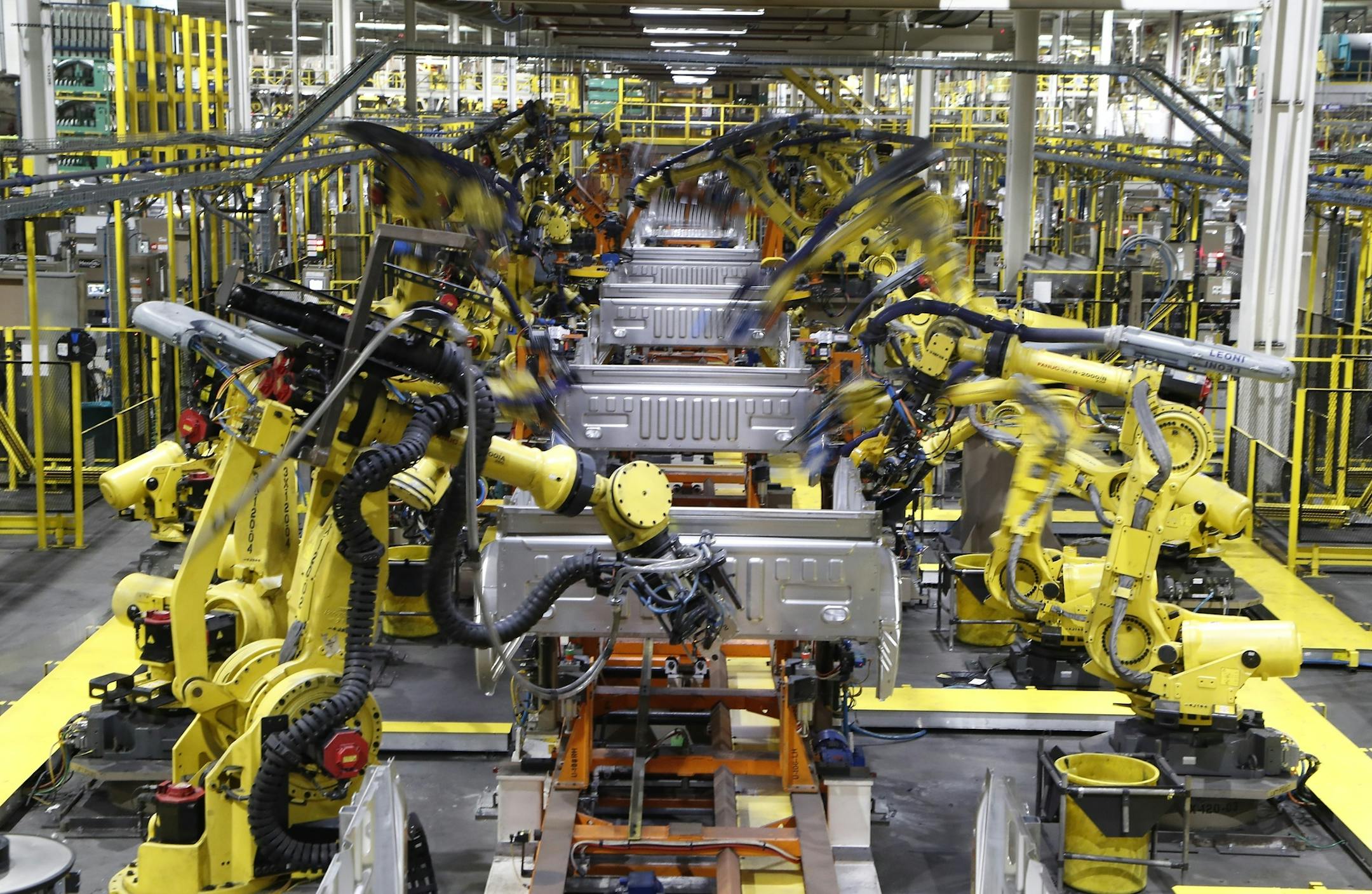 FILE - In this Sept. 27, 2018, file photo robots weld the bed of a 2018 Ford F-150 truck on the assembly line at the Ford Rouge assembly plant in Dearborn, Mich. Ford says it wants to reopen five North American assembly plants in April 2020 that were closed due to the threat of coronavirus. The three Detroit automakers suspended production at North American factories March 19 ago under pressure from the United Auto Workers union, which had concerns about members working closely at work stations