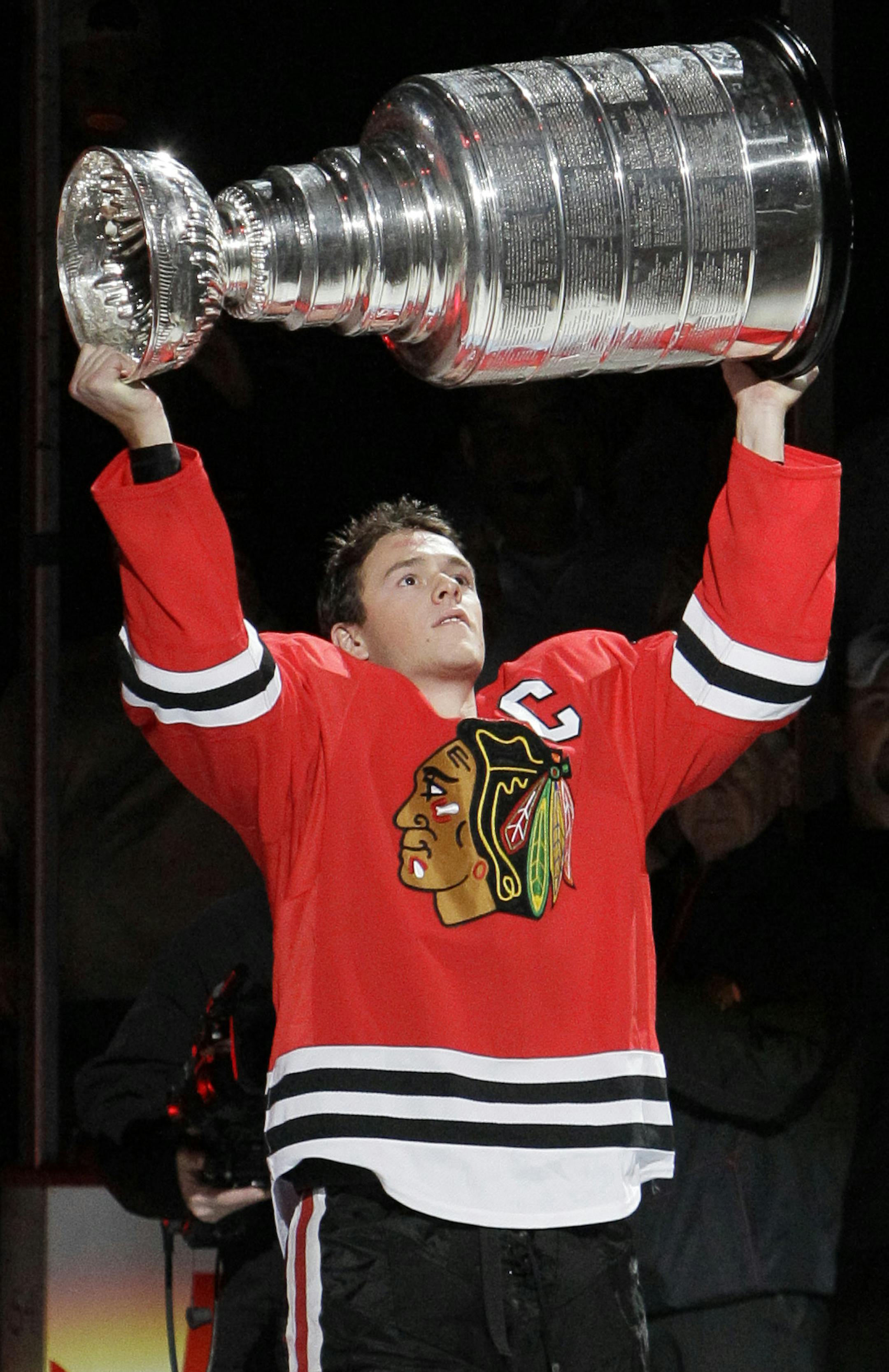 Chicago Blackhawks captain Jonathan Toews carries the Stanley Cup on to the ice during ceremonies before their NHL hockey game against the Detroit Red Wings Saturday, Oct. 9, 2010 in Chicago. (AP Photo/Charles Rex Arbogast) ORG XMIT: CXA108