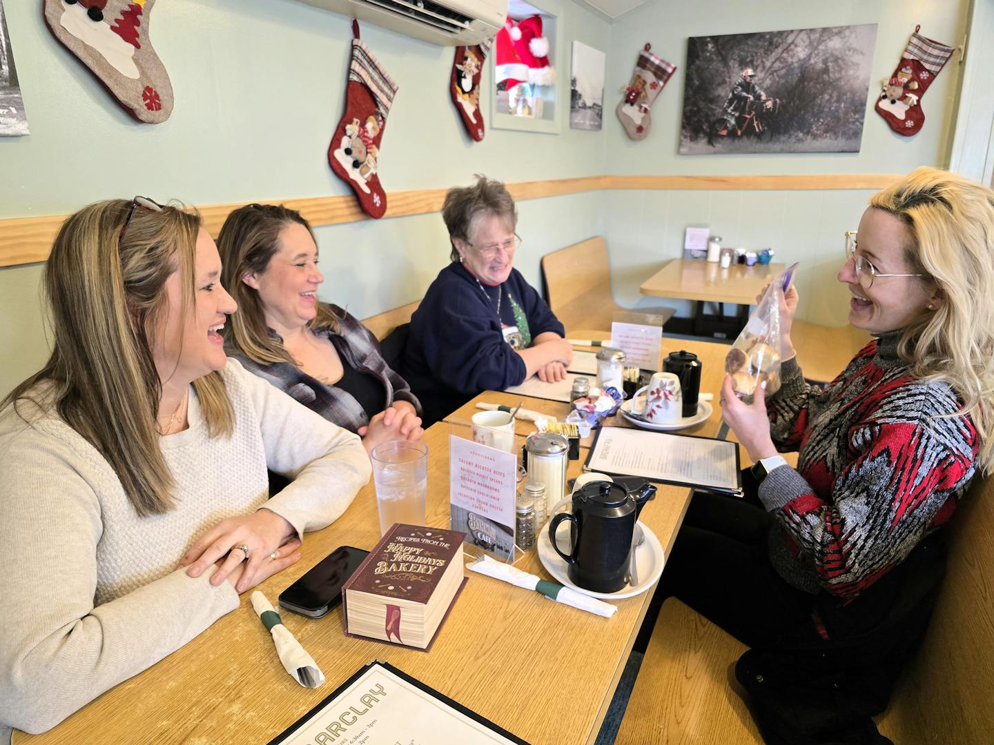 Rosie Grant, right, a researcher from Los Angeles, shows Tammy Frericks and Kim Hedlund (left and center) a homemade batch of their late mother Isabella Carlson's potato rolls that Grant made after seeing the recipe on Carlson's headstone. Also pictured is Kathy Soukup (right), the Ponto Lake cemetery manager. Photographed at the Barclay in Pine River, Minn., Dec. 17, 2024.