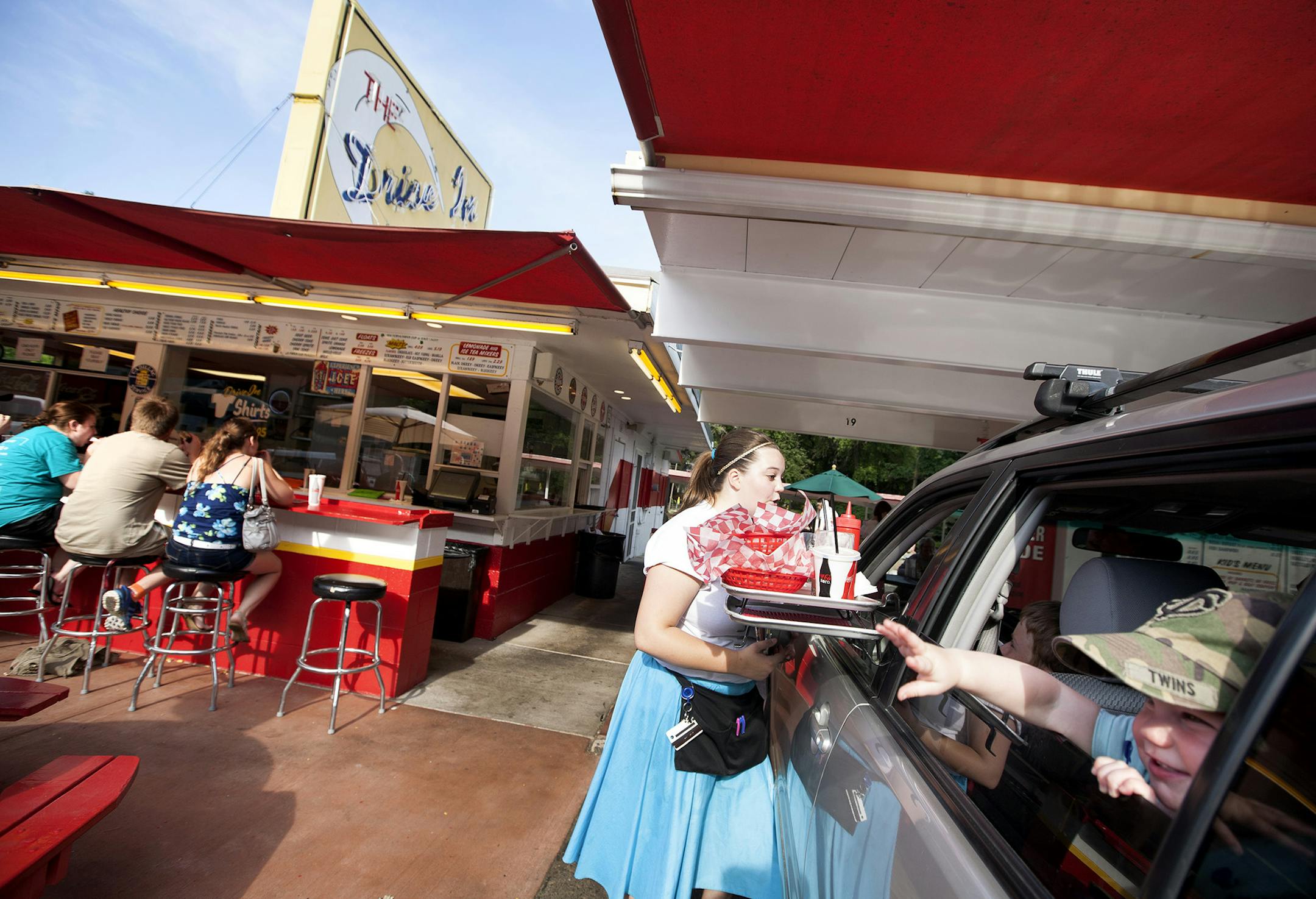 Lola Smestad, 16 months, reaches out from her car window as carhop Beth Peterson checks in for a dessert order at The Drive-In in Taylors Falls, June 26, 2014. (Courtney Perry/Special to the Star Tribune)
