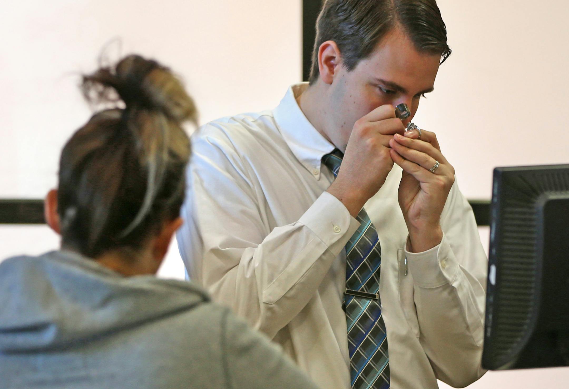 Pawnbroker Jesse Peterson used a magnifier to check out a diamond ring that was being pawned at the Pawn America store in Fridley.