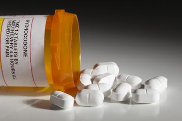 A bottle with a hydrocodone (the generic name for drug sold under other names by various pharmaceutical companies) label and hydrocodone tablets spill