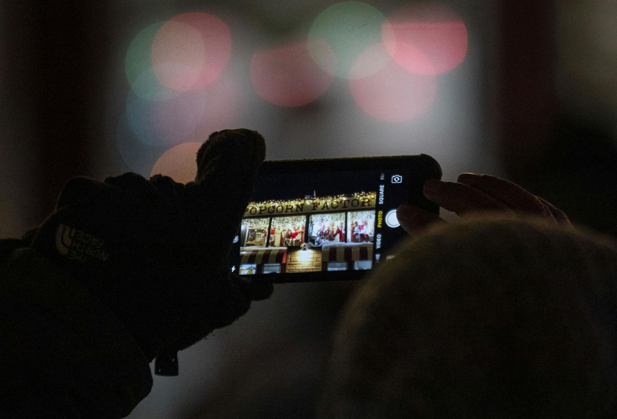 A woman took a photo with her iPhone of the animatronic elves atop the popcorn stand in Bentleyville on Tuesday December 3, 2019.