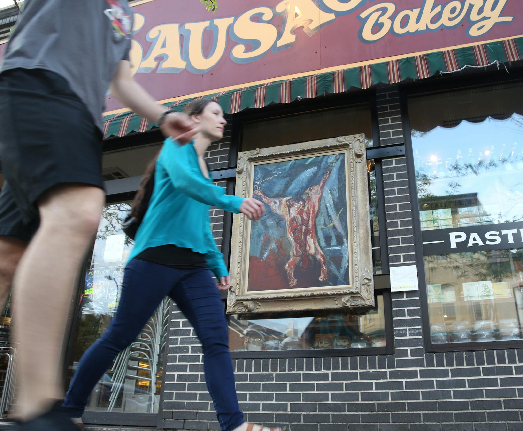 A copy of Rembrandt's "the Carcass" hung outside of Kramarczuk's deli as pedestrians walked passed. ] (KYNDELL HARKNESS/STAR TRIBUNE) kyndell.harkness@startribune.com In celebration of its centennial the Mpls Institute of Arts has placed high-quality reproductions of three paintings from its collection at unexpected sites around Mpls in Minneapolis Min., Thursday, May 7, 2015.